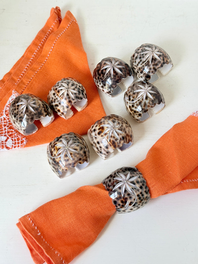 Set of eight vintage shell napkin rings with natural speckled patterning, photographed on a white surface