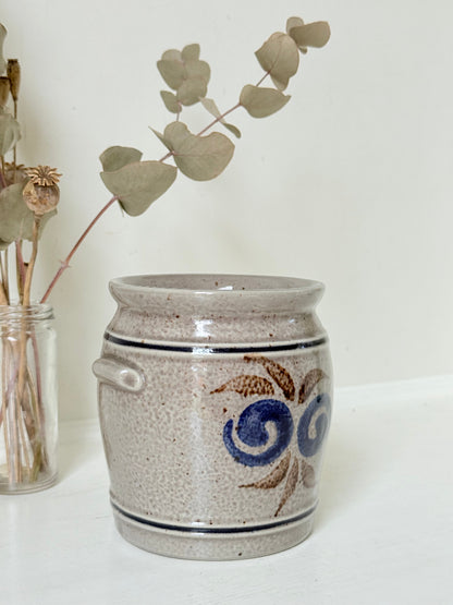 Vintage stoneware confit pot with blue and brown folk art design, photographed on a white surface