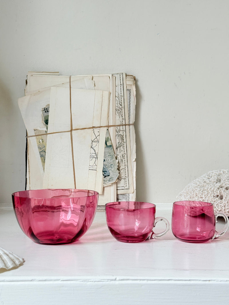 Trio of antique cranberry glass with sugar bowl, teacup, coffee can, clear glass handles and deep pink glass