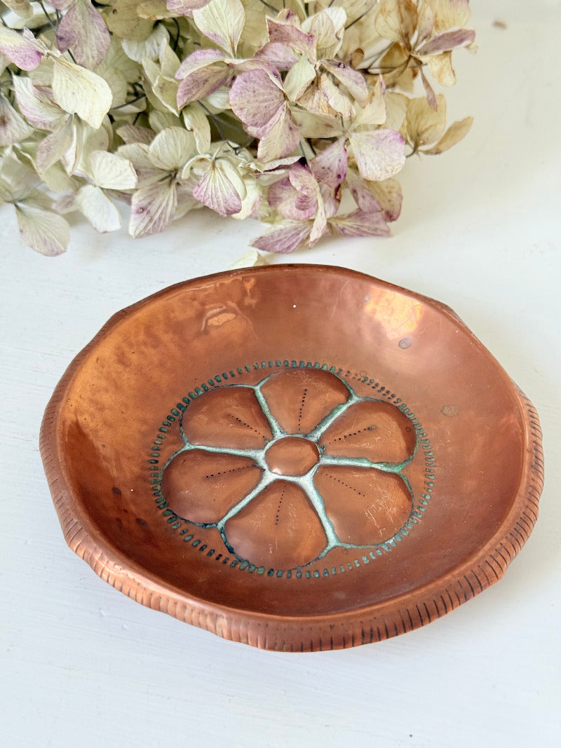 small vintage copper dish with cut-out floral centre photographed on white surface