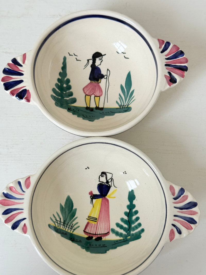 Pair of vintage French Quimper Breton figure snack bowls with painted side handles, photographed on a white surface