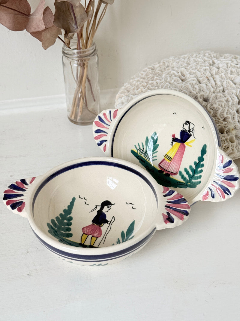 Pair of vintage French Quimper Breton figure snack bowls with painted side handles, photographed on a white surface