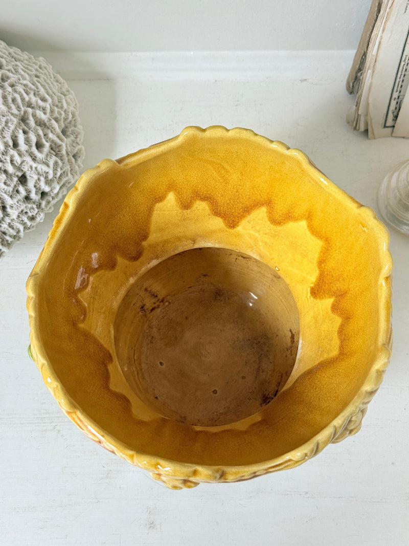 A yellow glazed ceramic bowl with a scalloped rim, photographed from a top-down perspective on a white surface.
