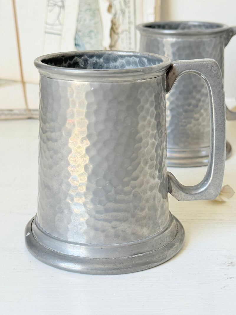 Pair of hammered English pewter tankards by E H Parkin of Sheffield, photographed on a white surface