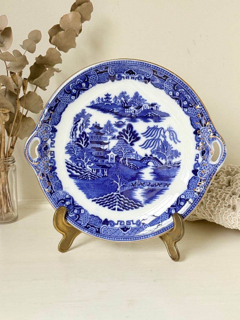 Antique Blue Willow serving plate with twin handles shown on a white surface.