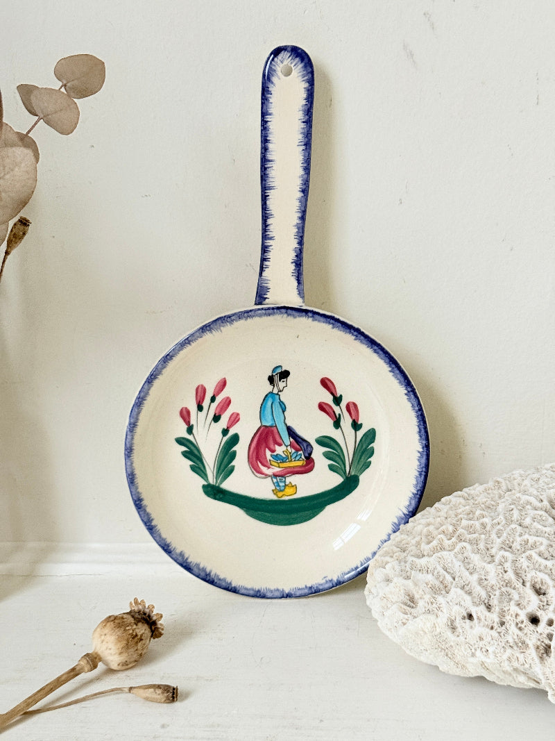 French Quimper faience handled wall dish with Petit Breton figure and blue rim, photographed on a white surface