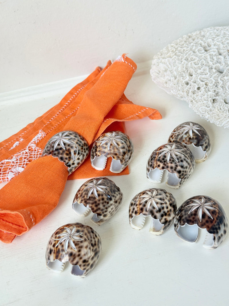 Set of eight vintage shell napkin rings with natural speckled patterning, photographed on a white surface