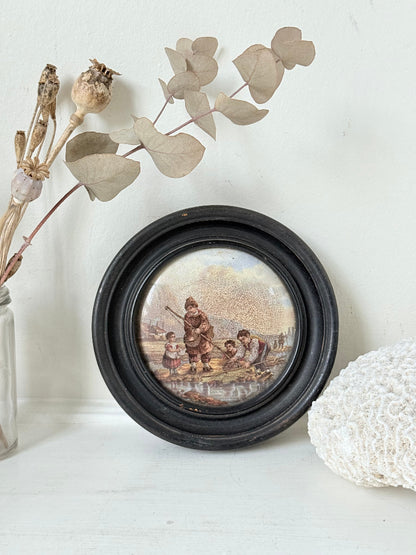 Antique Prattware framed ceramic lid with rural family scene photographed on a white surface.