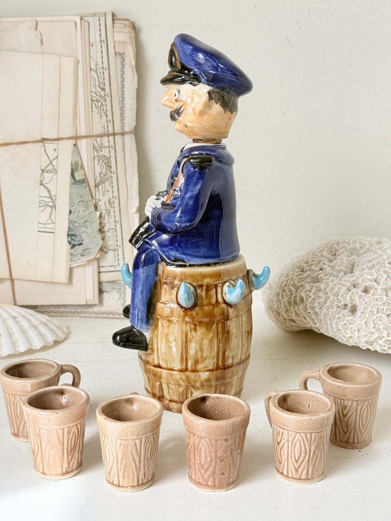 Vintage figural ceramic decanter set with captain, navy blue uniform, barrel base and 6 matching barrel shot cups