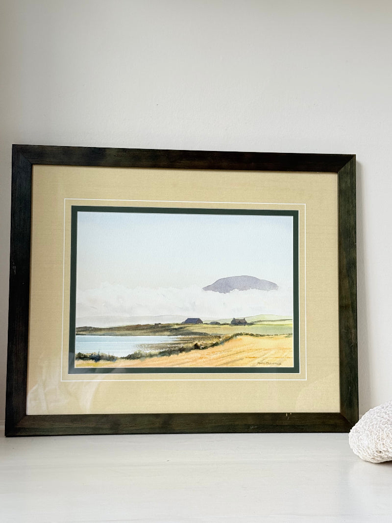 Framed Scottish watercolour coastal landscape by Martin W. M. Prentice in green frame with double mount, on white surface.