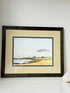 Framed Scottish watercolour coastal landscape by Martin W. M. Prentice in green frame with double mount, on white surface.
