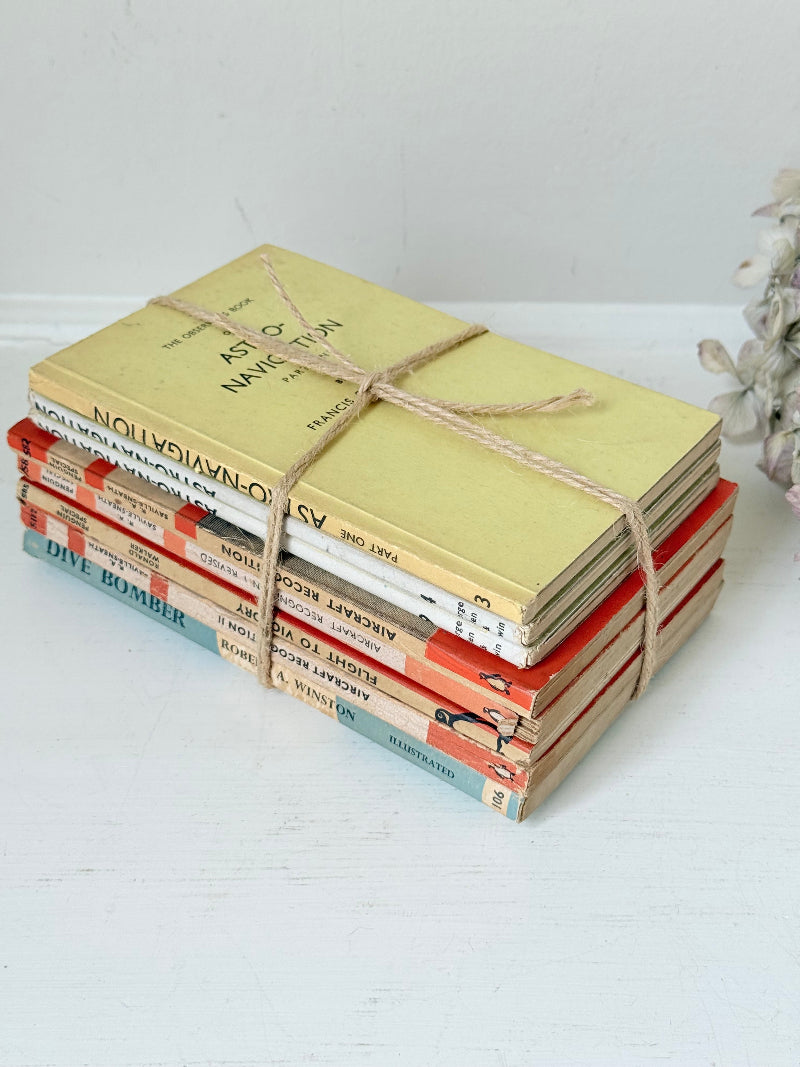 Bundle of vintage Penguin paperback books in orange and cream tones tied with twine, photographed on a white surface