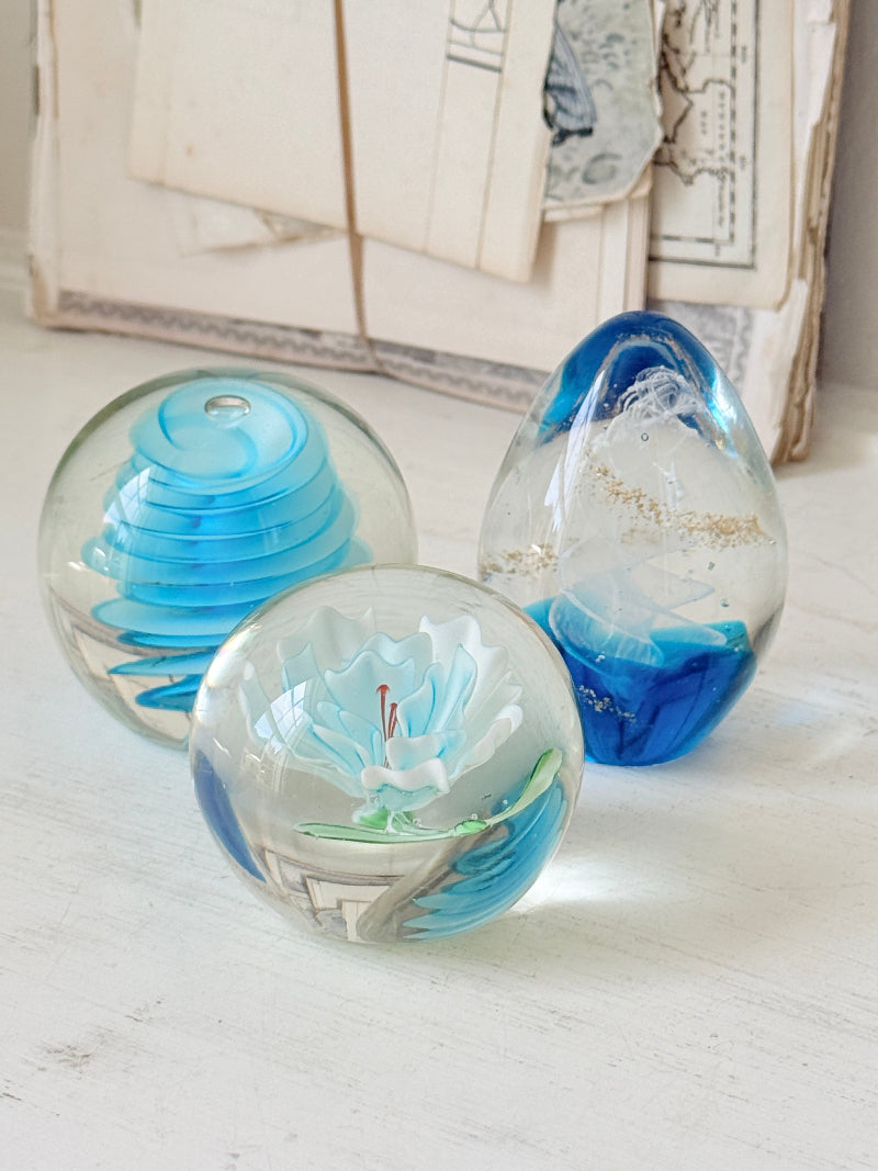 Trio of vintage turquoise blue glass paperweights with swirl, ribbed and floral detail in clear coloured glass