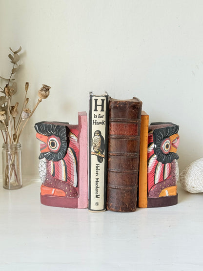 Vintage wooden owl bookends hand painted in red and orange tones, displayed on a white surface beside dried flowers.
