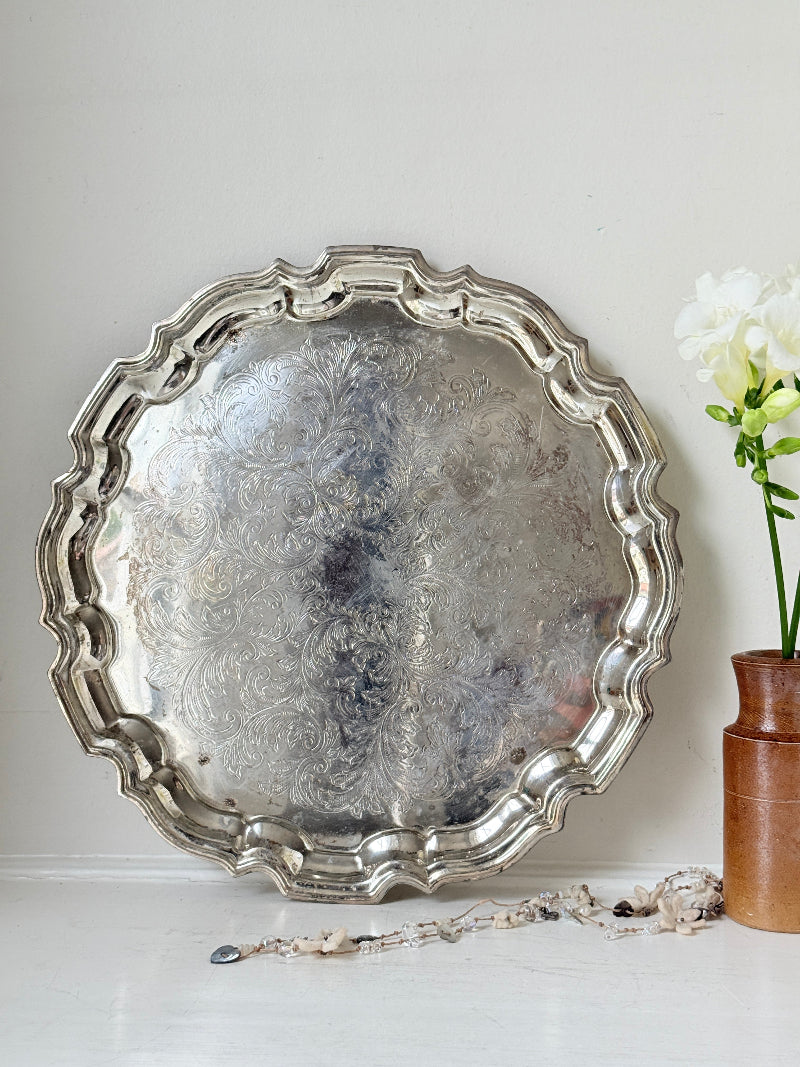 Vintage silver toned round serving tray with piecrust edge, aged patina and decorative scalloped rim for interior styling