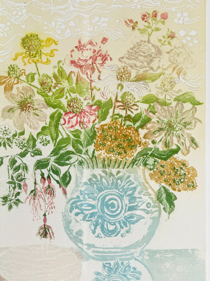 A vintage-style floral illustration featuring a bouquet of pink, yellow, white, and green flowers arranged in a light blue patterned vase against a cream background with subtle decorative borders.