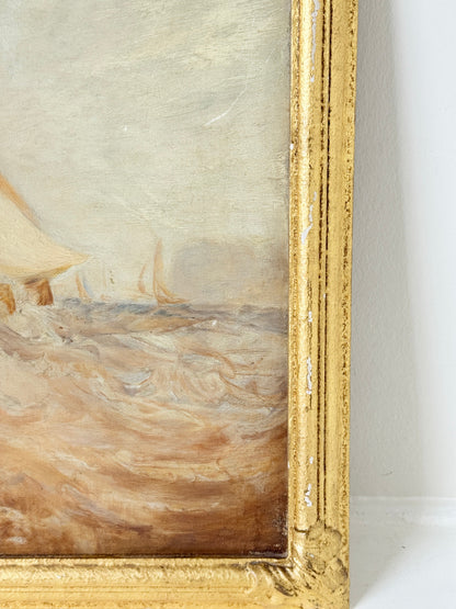 Close-up of an oil painting depicting a coastal scene with a sailboat on a sandy beach, framed in an ornate distressed gold frame.