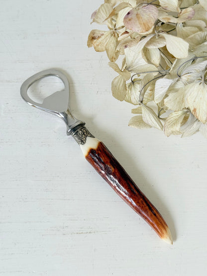 vintage antler handle bottle opener with stainless steel top photographed on white surface
