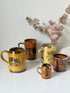 Set of 5 Ridgways stoneware mugs photographed on a white surface in amber brown glaze with black Coaching Days and Coaching Ways transfer scenes