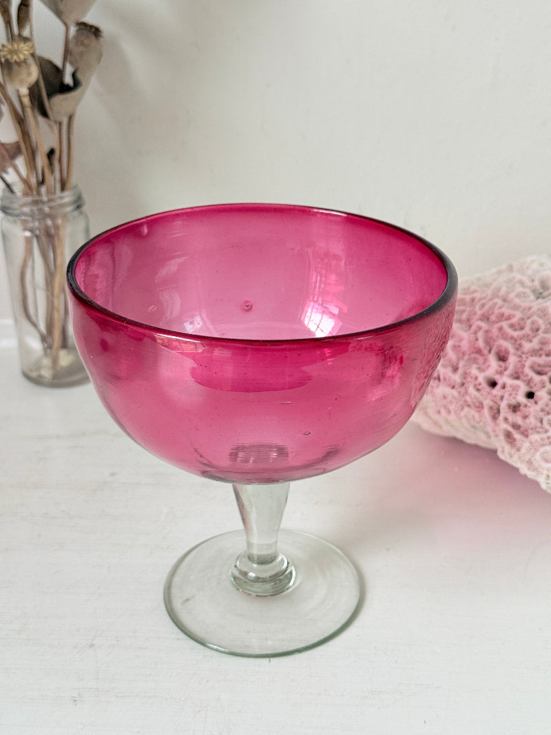 Vintage cranberry glass bonbon dish with clear stem and foot, photographed on a white surface