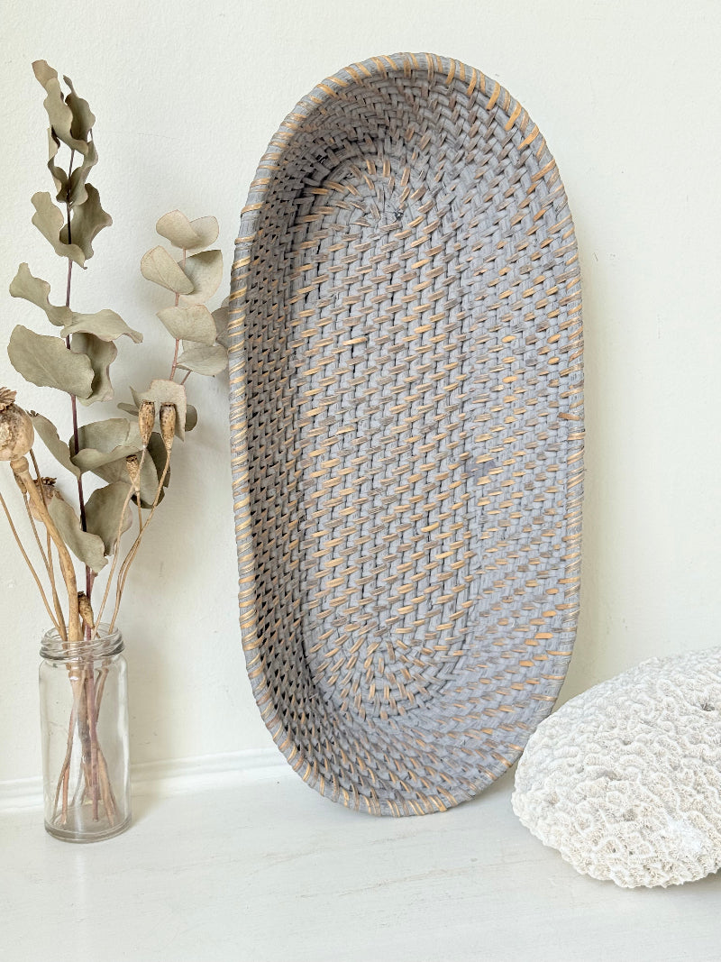 Vintage grey woven bread basket with oval shape and raised rim, photographed on white surface.