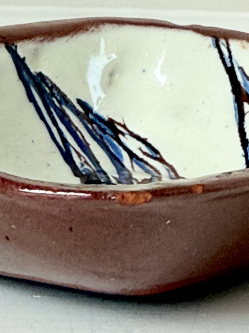 Vintage studio pottery soap dish with hand painted blue bird motif and terracotta rim, photographed on a white surface