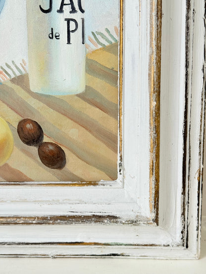 Still life oil painting showing fruit bowl and striped jug on a blue background, framed in white wood, photographed on a white surface.