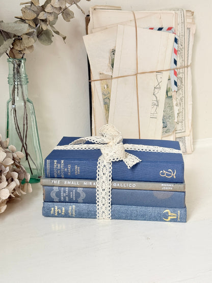Bundle of vintage blue cloth books with gilt spines tied with ivory lace ribbon for shelf and table styling
