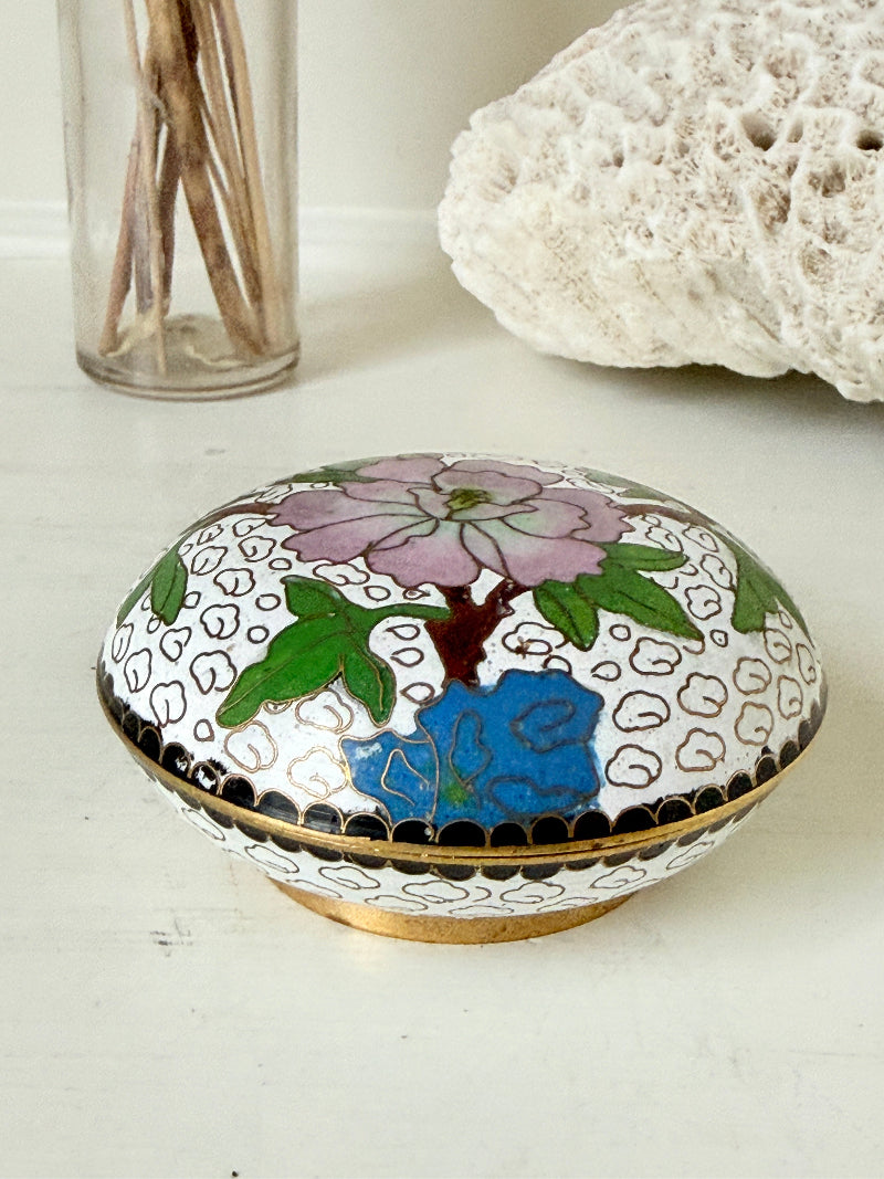 Vintage brass and enamel cloisonne trinket box with floral lid and turquoise interior photographed on a white surface