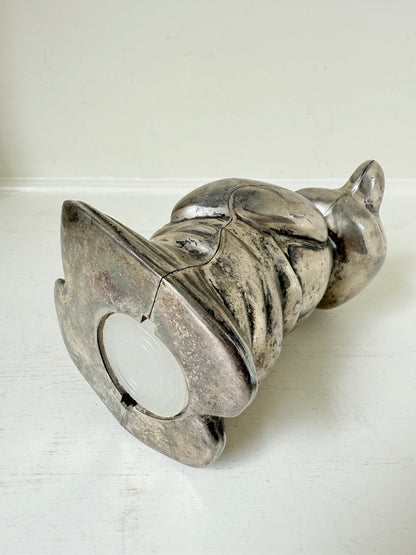 Vintage silver tone metal bear money box with coin slot on top, photographed on a white surface.