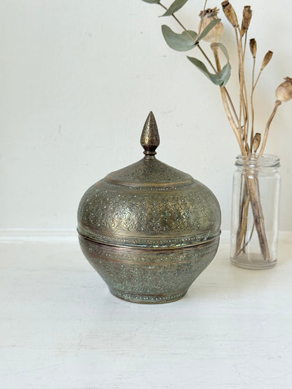 Indian Benares brass lidded jar with floral engraving and finial, photographed on a white surface