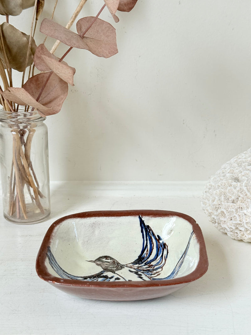Vintage studio pottery soap dish with hand painted blue bird motif and terracotta rim, photographed on a white surface