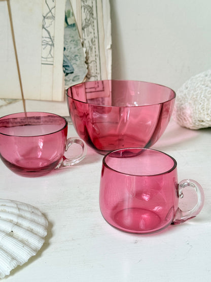 Trio of antique cranberry glass with sugar bowl, teacup, coffee can, clear glass handles and deep pink glass