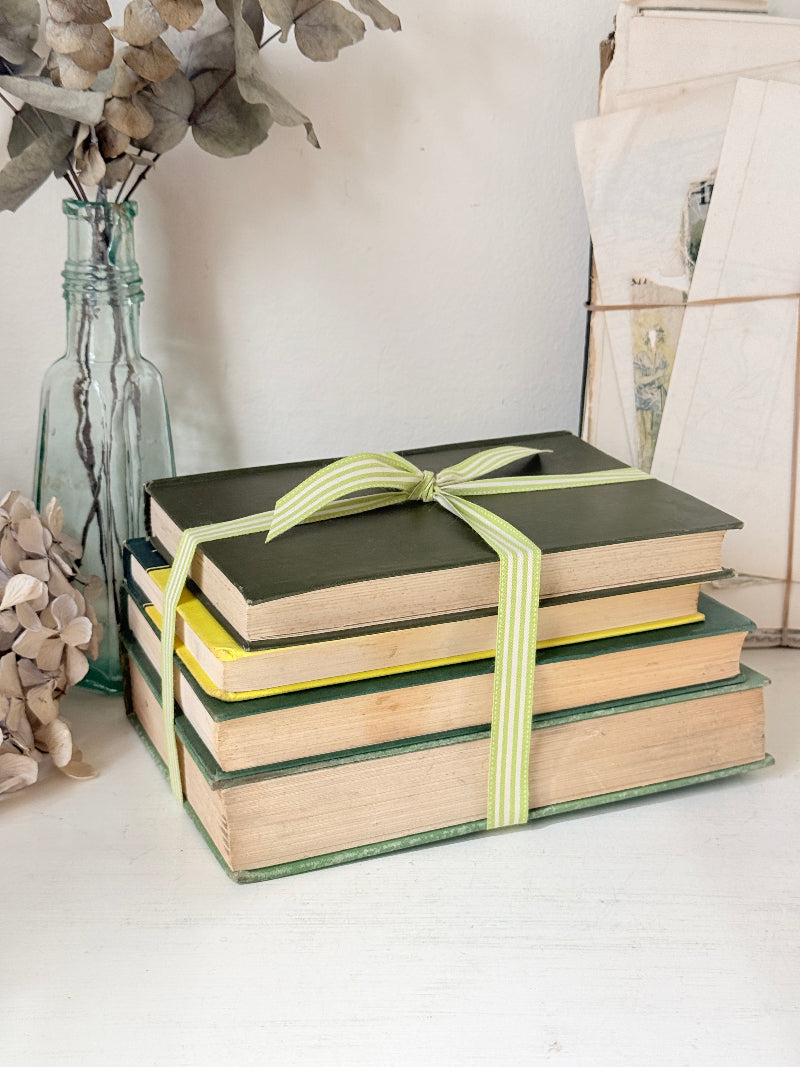 Bundle of vintage sage and olive green cloth books with red spine detail tied with a pale ribbon for styling
