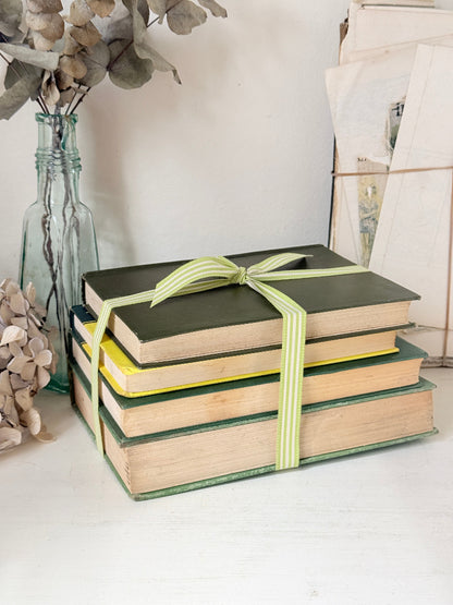 Bundle of vintage sage and olive green cloth books with red spine detail tied with a pale ribbon for styling
