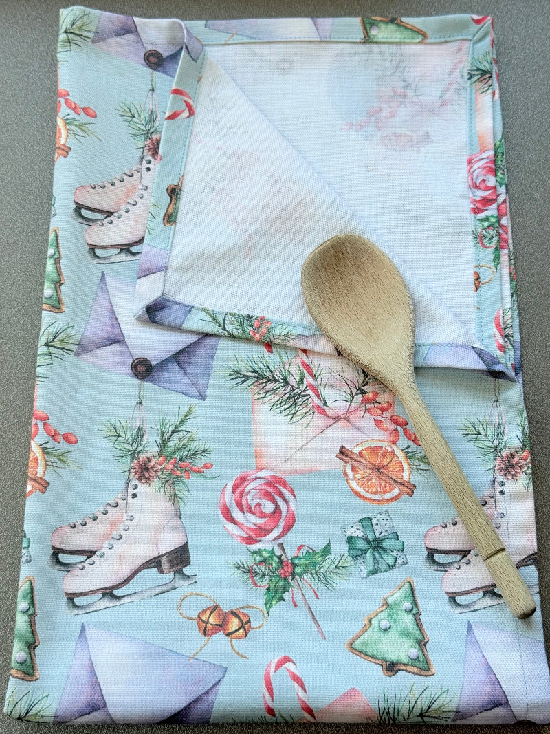 Blue Loft Christmas cotton tea towel with ice skate and candy pattern photographed on a white surface.