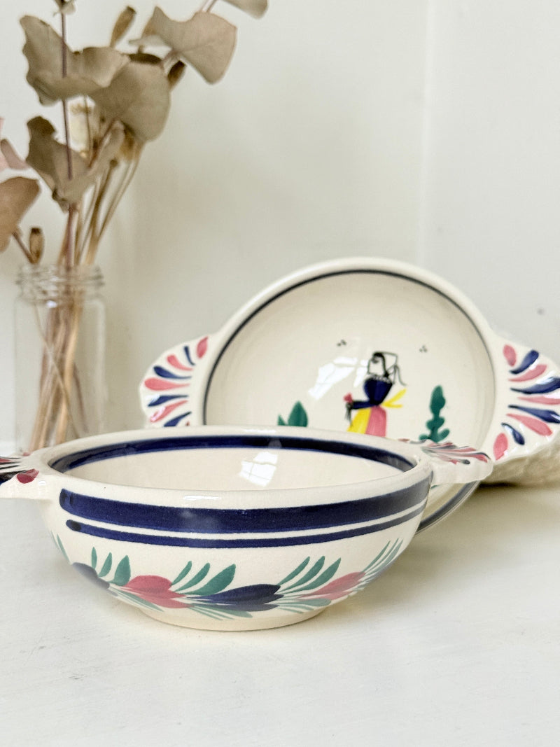 Pair of vintage French Quimper Breton figure snack bowls with painted side handles, photographed on a white surface