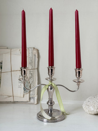 Silver plate three light candelabra with curved arms and domed base holding red taper candles