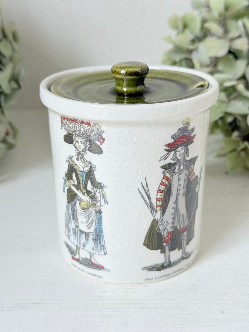 vintage holkham pottery condiment pot with green lid and illustrated figures photographed on white surface