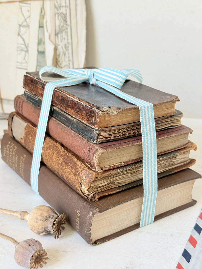 Vintage decorative brown book bundle with aged hardback covers tied with blue stripe ribbon for bookshelf and table styling