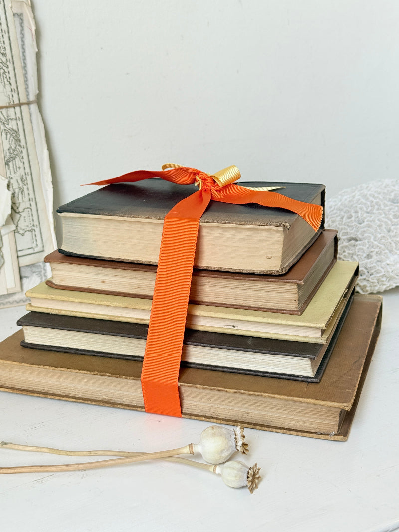 Vintage decorative book bundle in orange and brown with aged hardback covers and bright orange ribbon for shelf styling