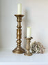 Pair of vintage wooden candlesticks, one tall and one small, in golden-toned finish, styled with pillar candles on a white surface.