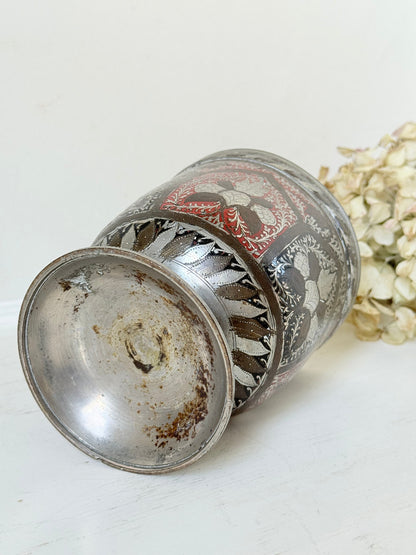 vintage indian metal lassi cup with red and white enamel motifs, styled with dried hydrangeas on a white surface