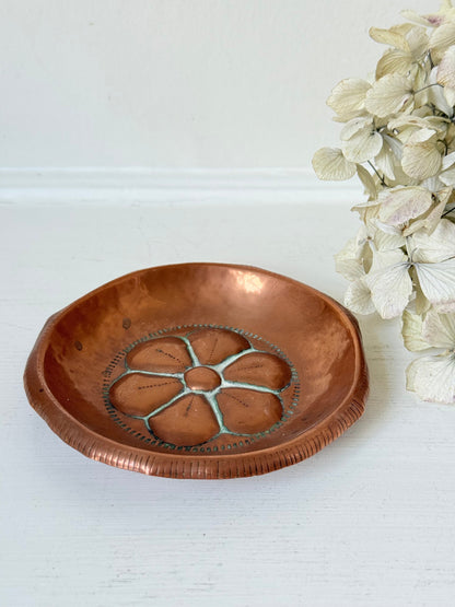 small vintage copper dish with cut-out floral centre photographed on white surface