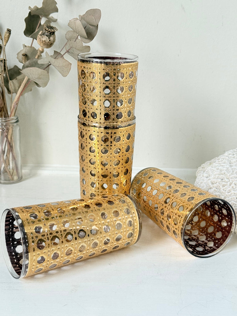 Set of 4 vintage gold rattan effect glasses with pierced lattice sleeves, photographed on a white surface