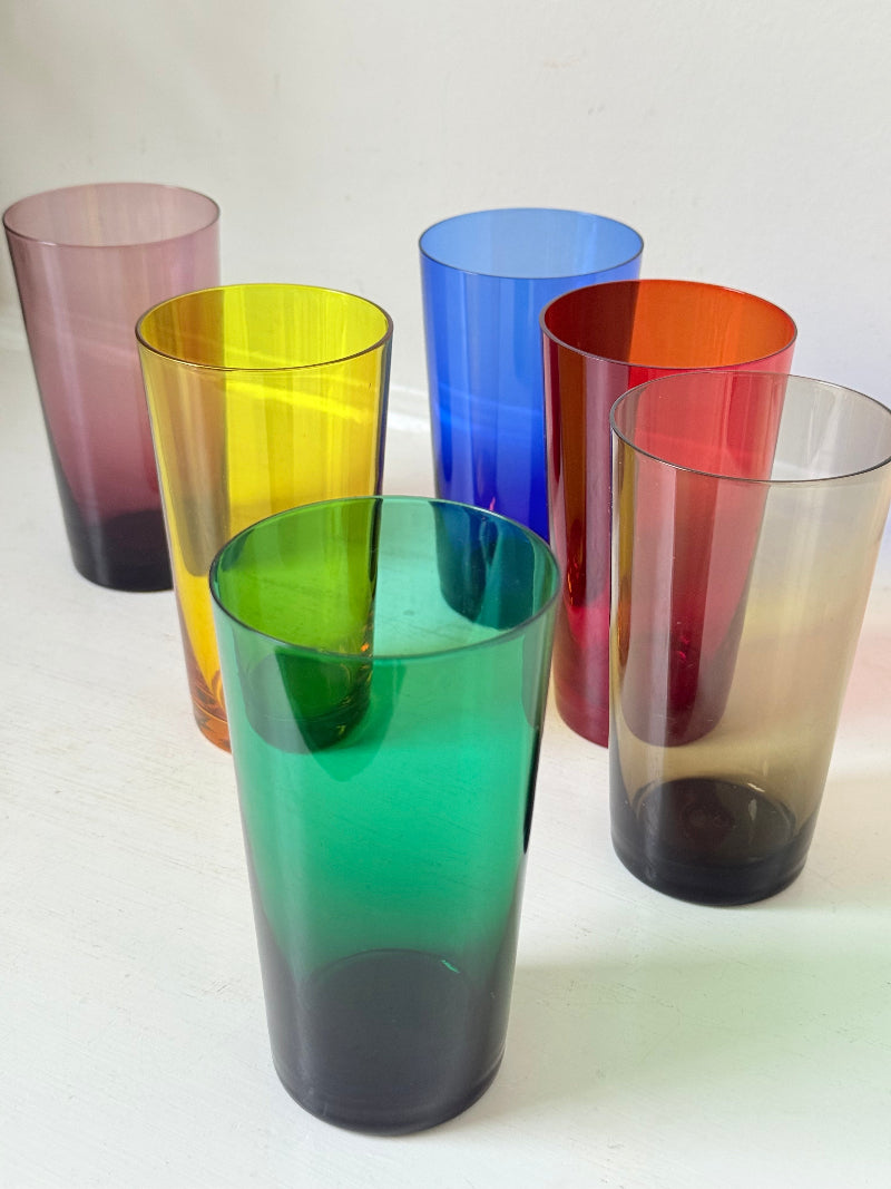 Set of six mid-20th century Boussu coloured glass tumblers in green, yellow, red, violet, blue and brown, photographed on white surface.
