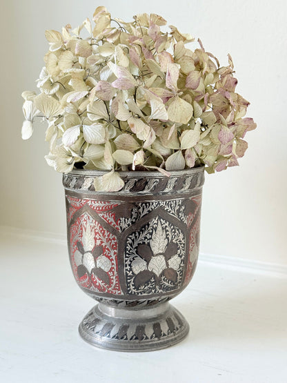 vintage indian metal lassi cup with red and white enamel motifs, styled with dried hydrangeas on a white surface