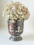 vintage indian metal lassi cup with red and white enamel motifs, styled with dried hydrangeas on a white surface