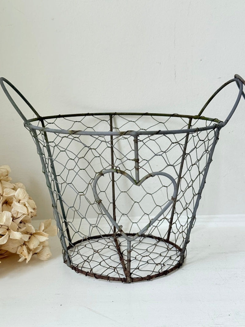 Pair of vintage decorative wire baskets with heart detail and aged patina photographed on a white surface