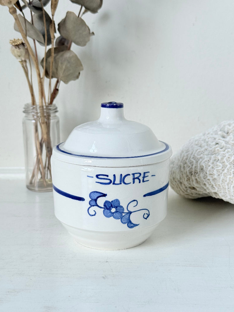 Vintage French blue and white studio pottery sugar bowl with lid, photographed on a white surface.